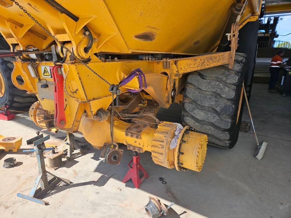 Yellow construction vehicle's rear axle undergoing repair. Jack stands support the vehicle— Cap Coast Maintenance In Alton Downs, QLD
