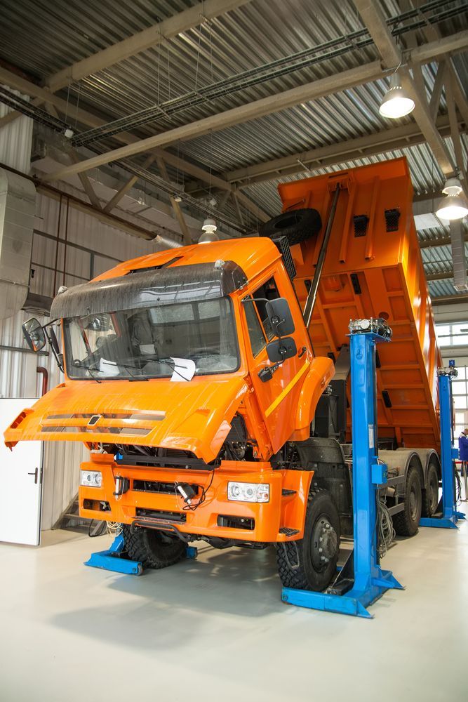 Orange Dump Truck Raised on a Lift Inside a Garage — Cap Coast Maintenance In Alton Downs, QLD
