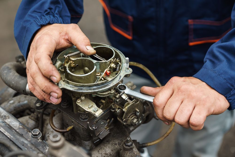 A Mechanic Using a Wrench to Work on a Car Carburetor — Cap Coast Maintenance In Alton Downs, QLD
