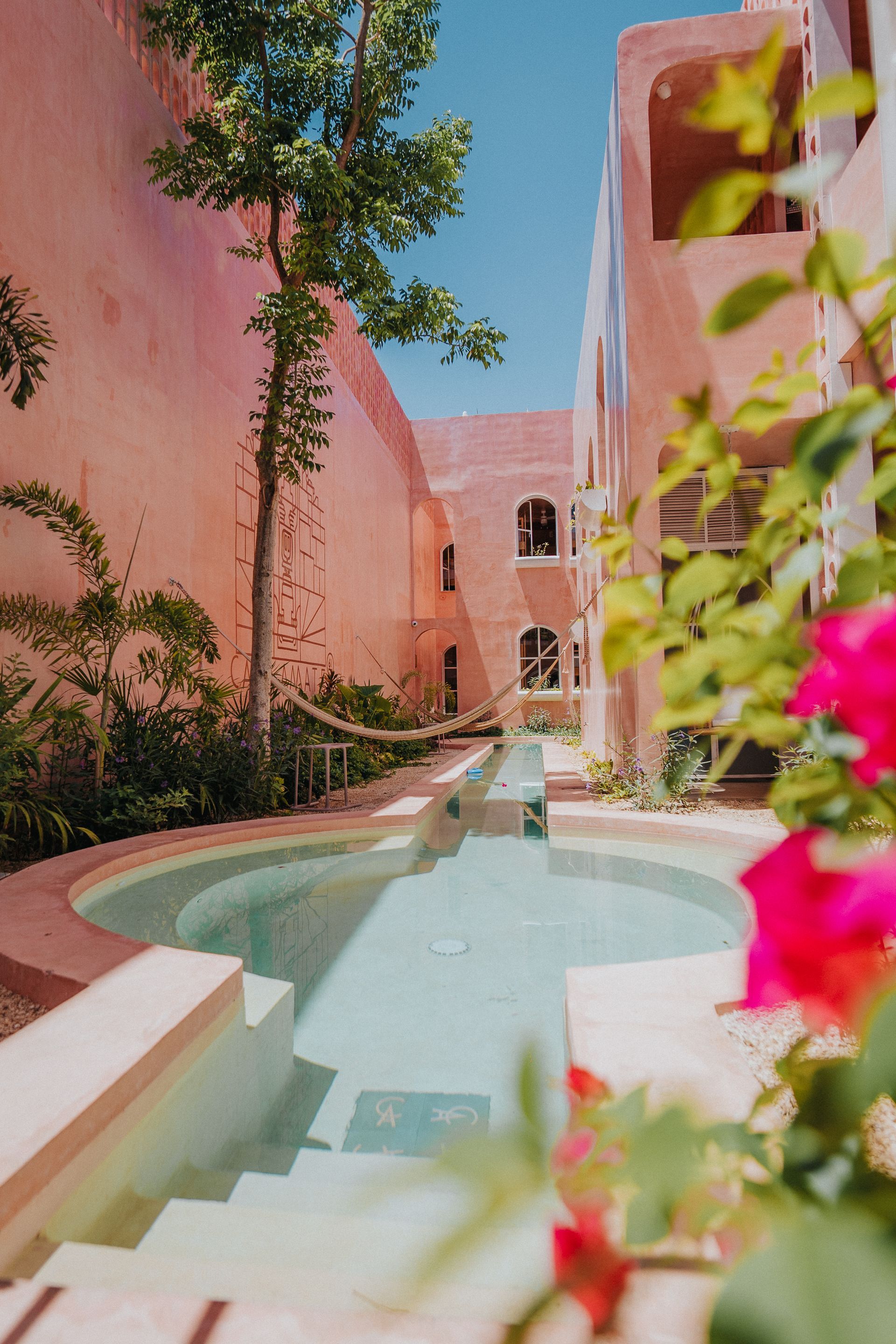 Hay una piscina en el medio de un patio entre dos edificios.
