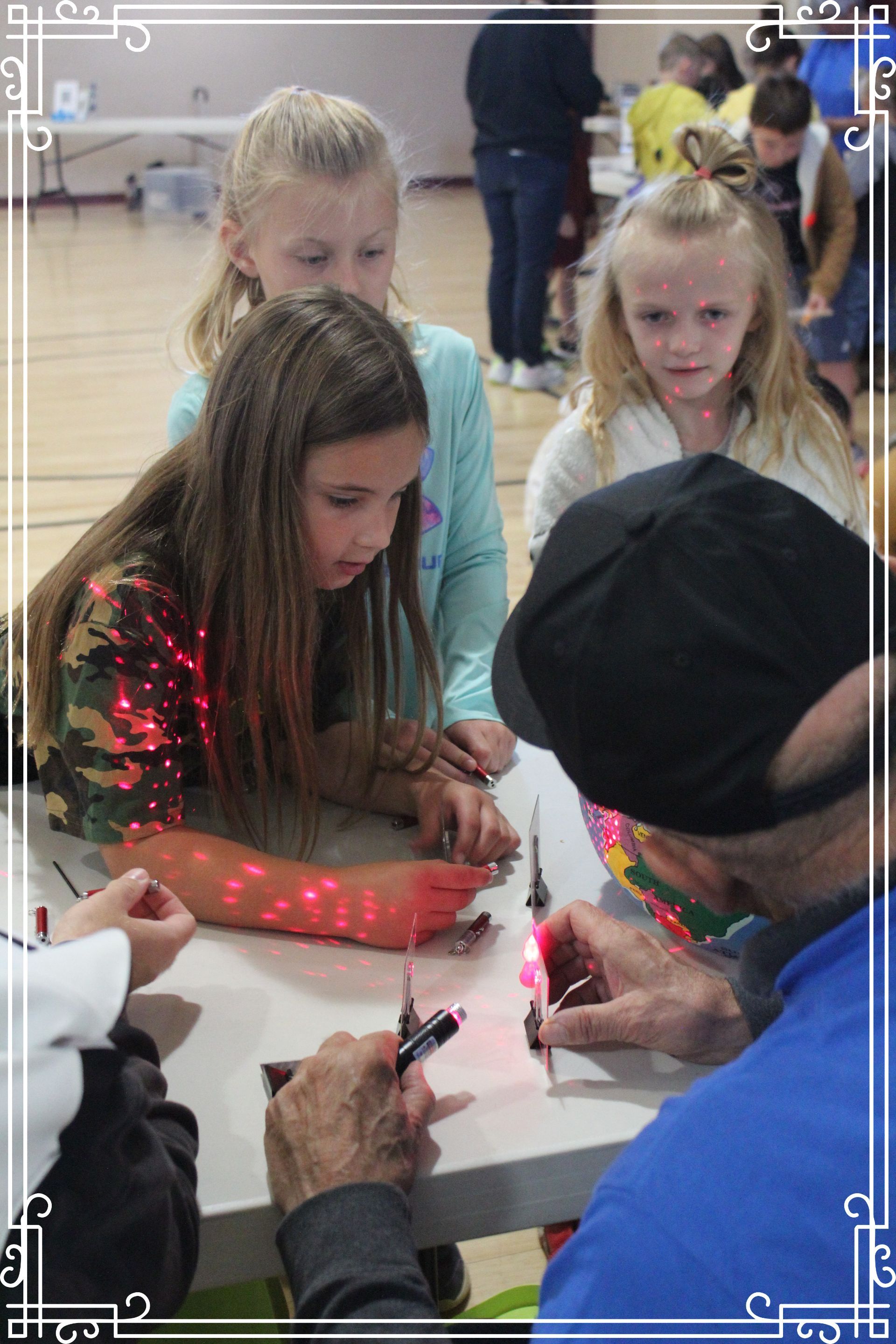 A group of young girls are sitting at a table with a man.