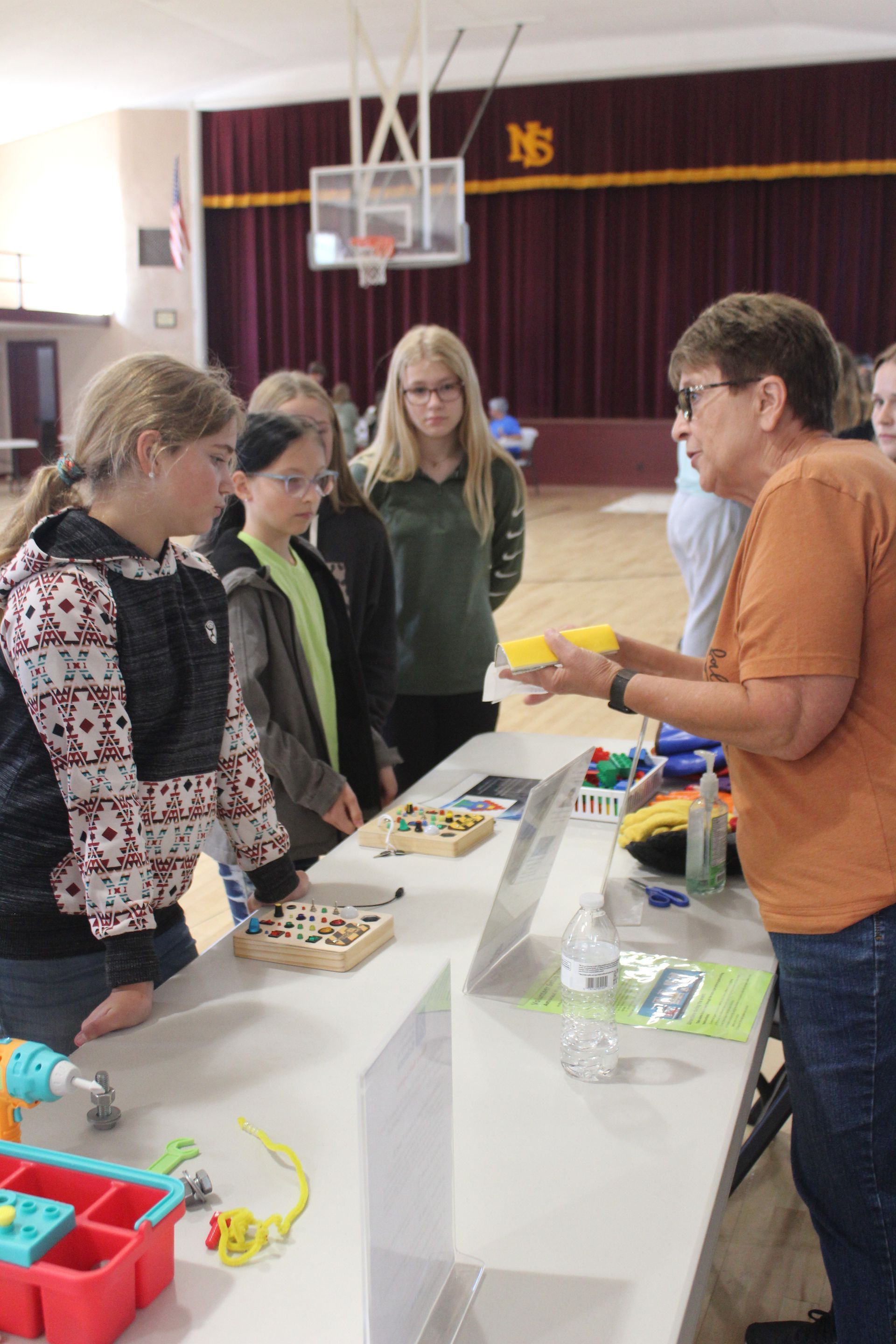 A woman is talking to a group of children at a table.