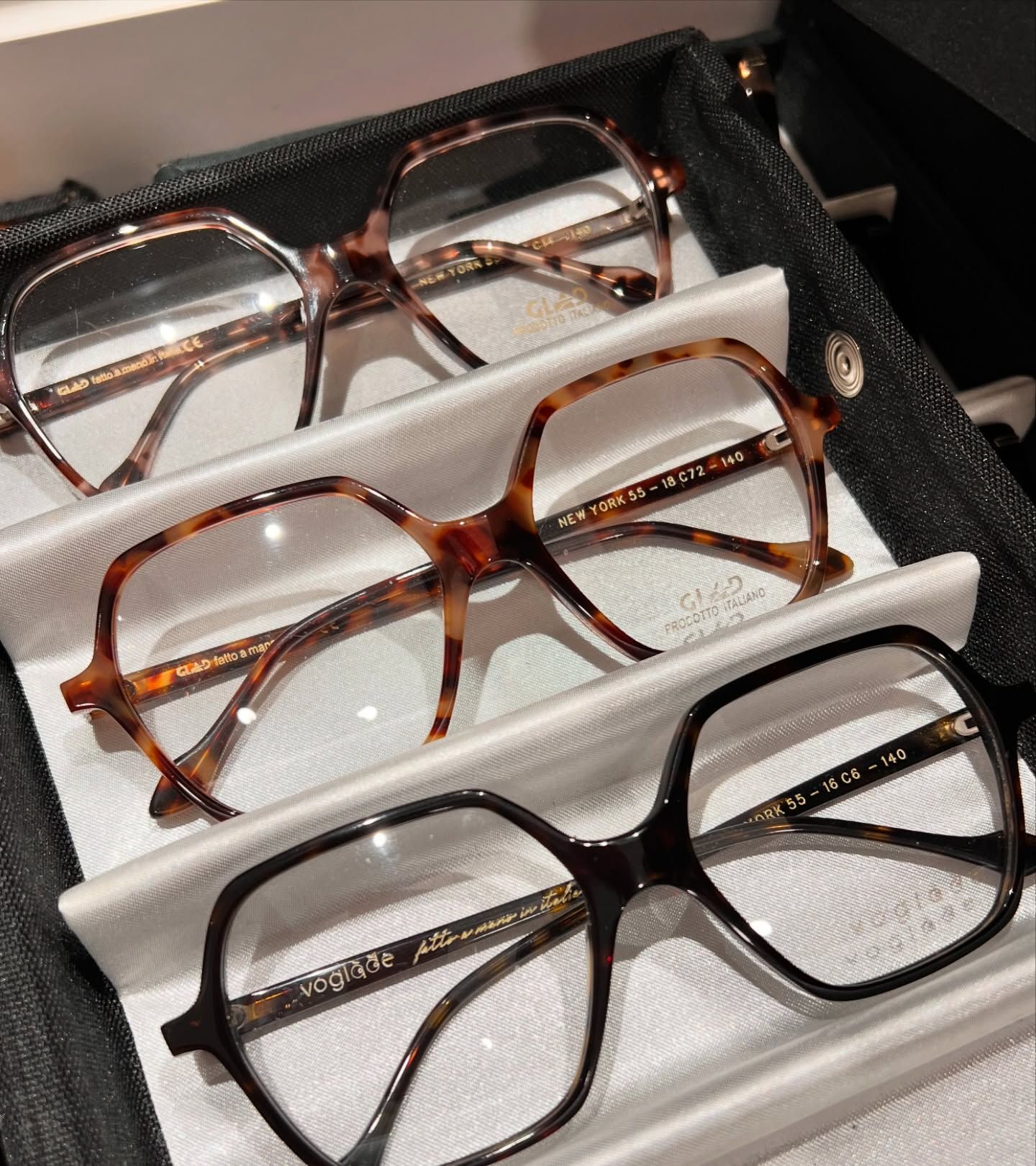 Tre paia di occhiali con montatura esagonale, tartarugata e nera, riposti in un astuccio con scomparti multipli.