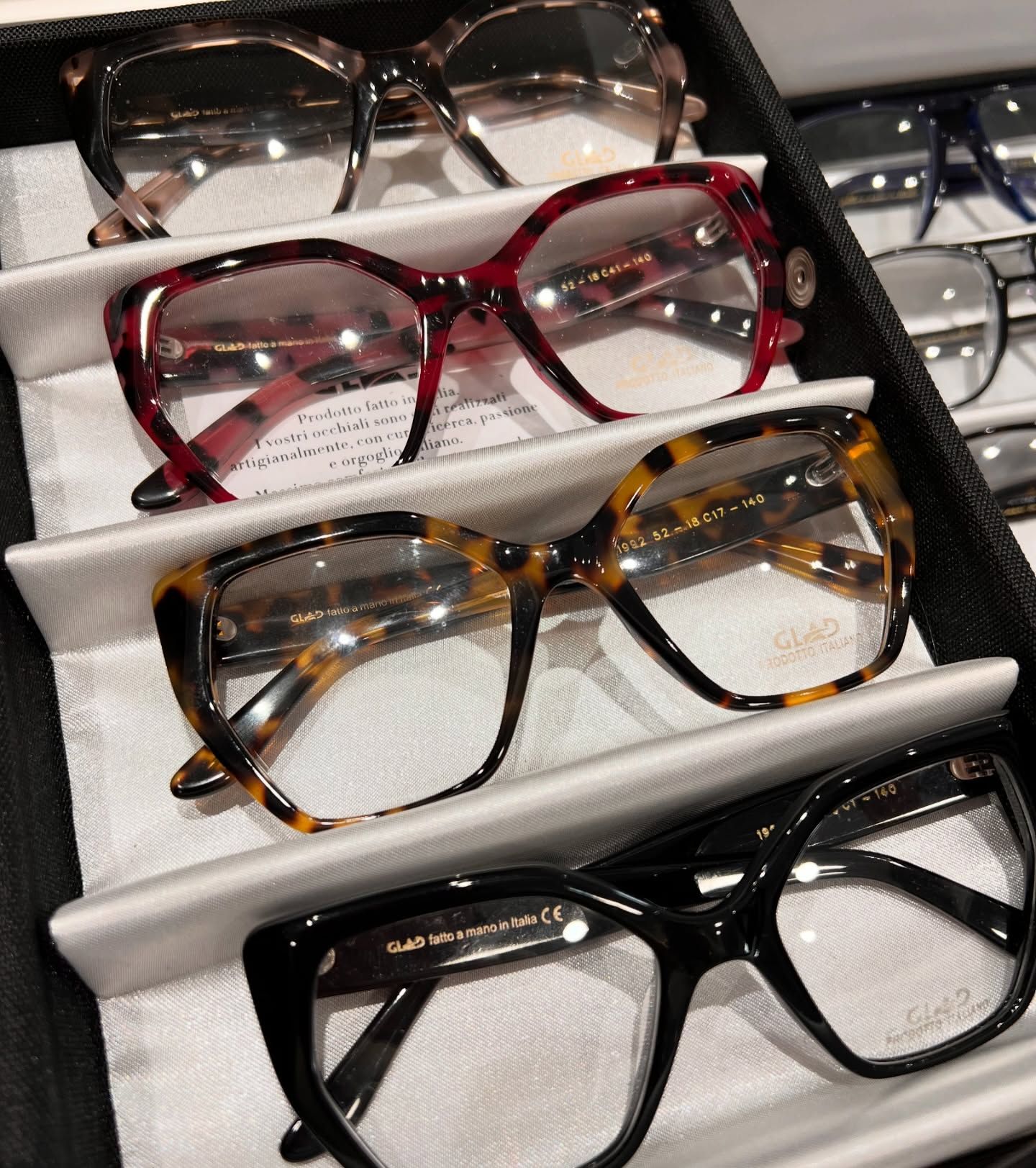 Un primo piano di un vassoio con quattro paia di eleganti bicchieri dalla montatura spessa, in vari colori, tra cui tartarugato.