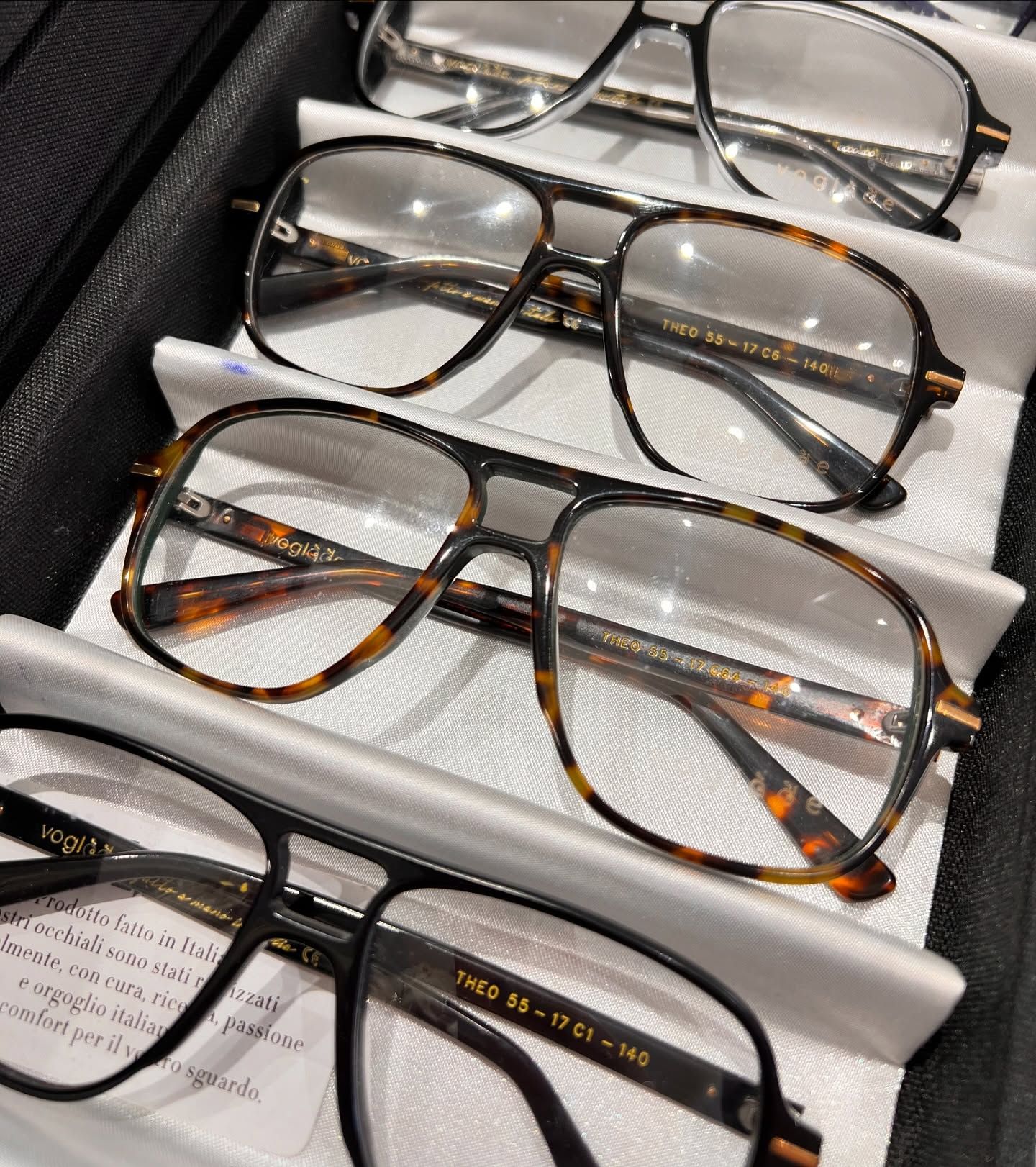 Primo piano di quattro paia di occhiali da aviatore con montatura tartarugata, disposti in un astuccio bianco foderato.