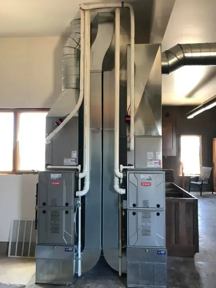 Two Bryant HVAC units installed in a room. Metal ductwork and pipes visible.