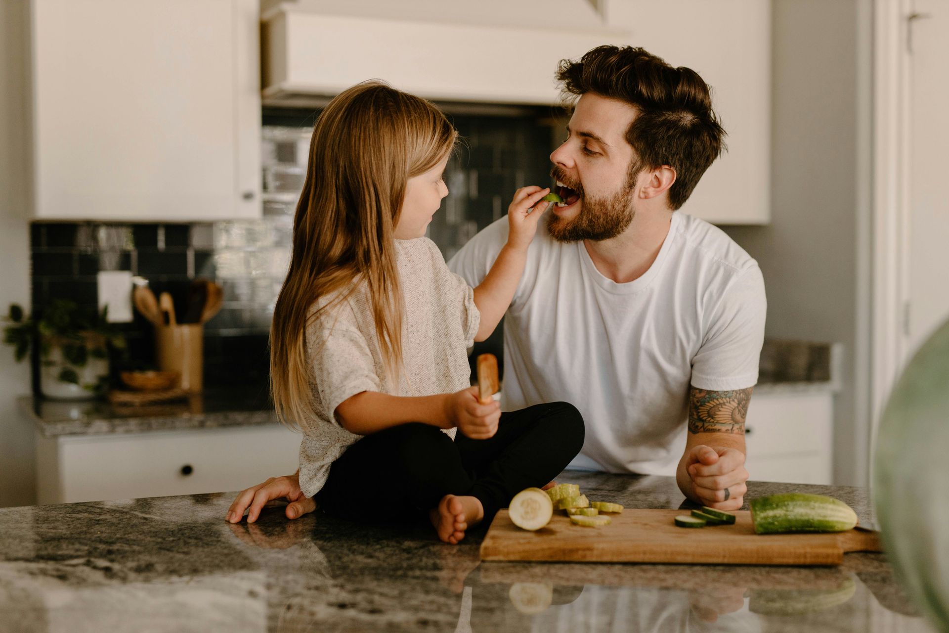 Woman at desk with hands clasped, listening to a man in a suit reviewing documents. Office setting.