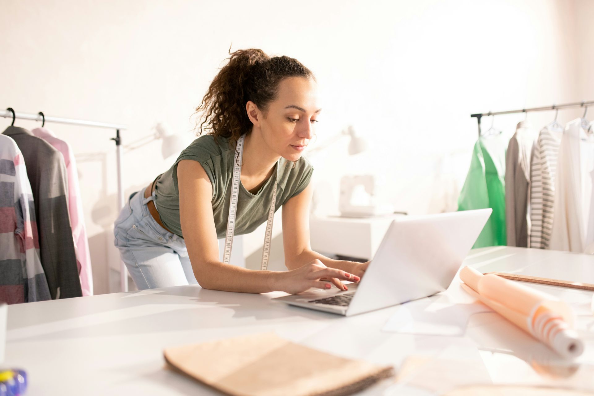 Woman at desk with hands clasped, listening to a man in a suit reviewing documents. Office setting.