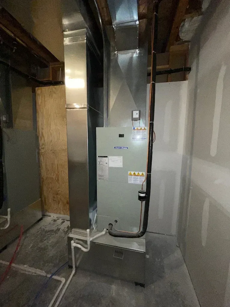 Woman at desk with hands clasped, listening to a man in a suit reviewing documents. Office setting.
