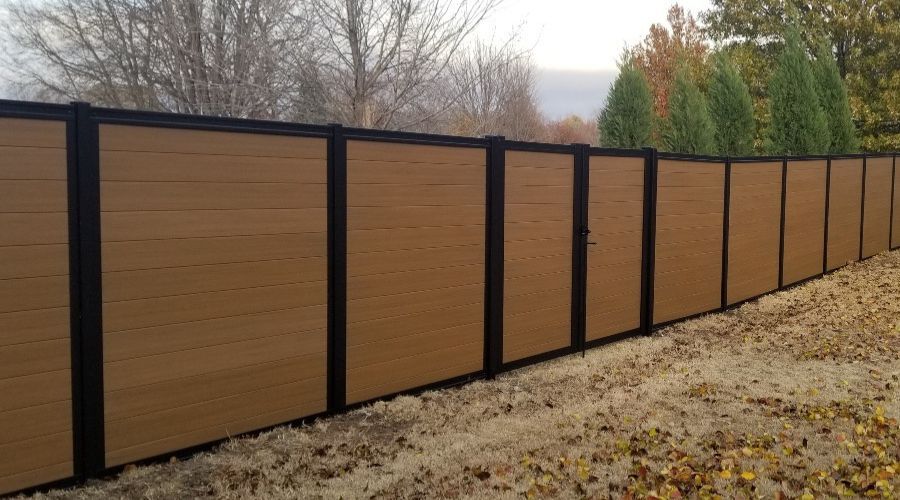 Modern horizontal wood-look composite privacy fence with a black metal frame and matching gate, providing a high-end security barrier for a commercial property.