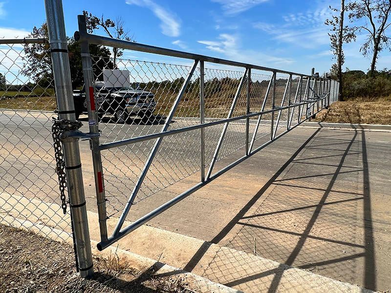 A chain link fence with a gate on the side of the road.