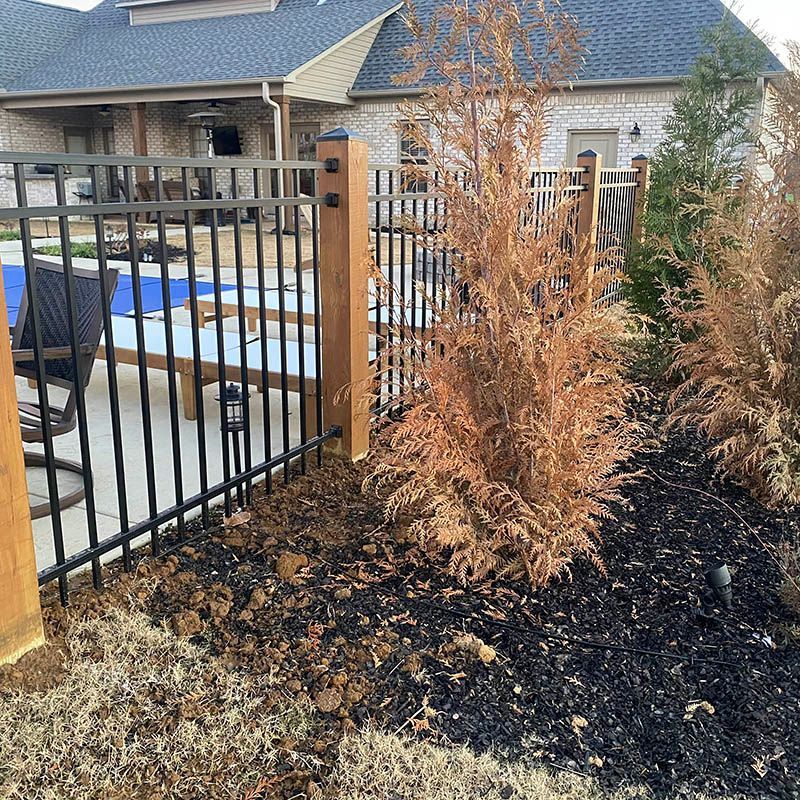 A fence with a wooden post in front of a house.