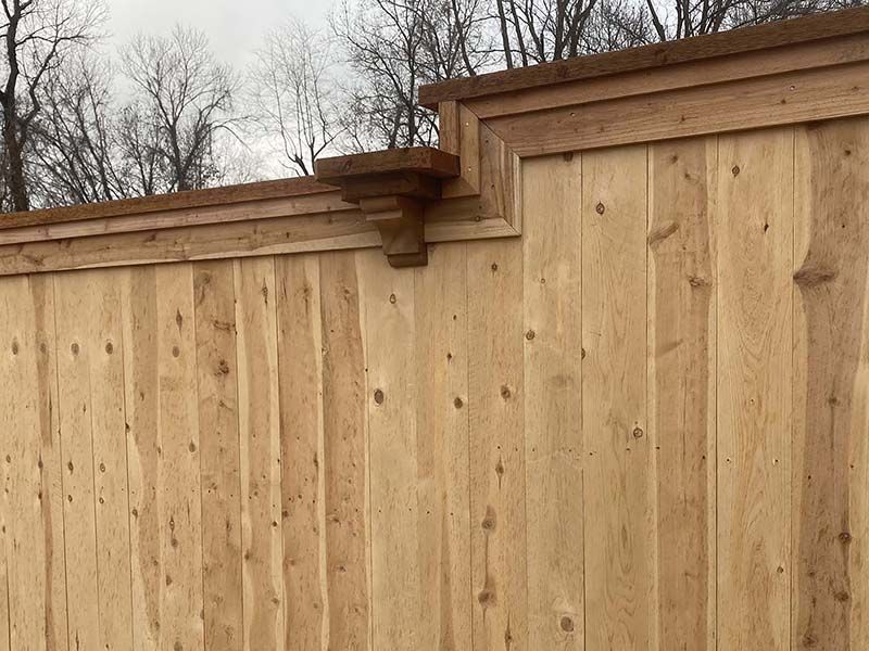 A close up of a wooden fence with trees in the background.
