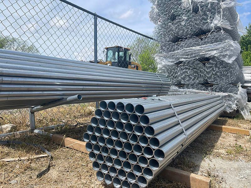 A bunch of metal pipes are stacked on top of each other in a field.