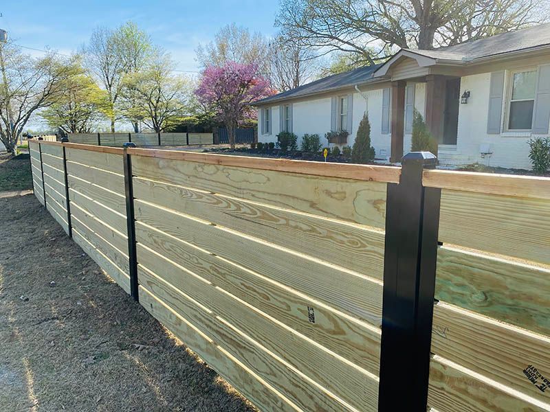 A wooden fence is in front of a white house.