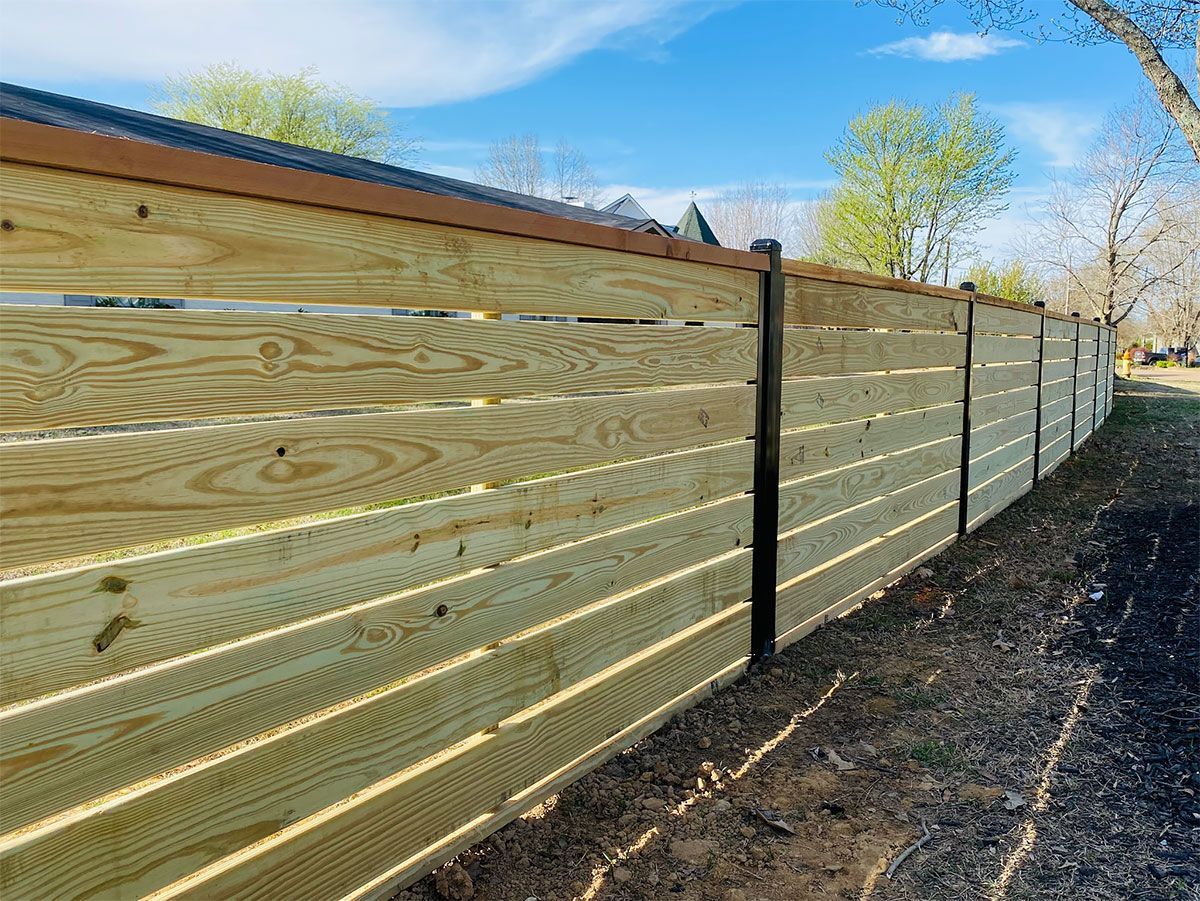 A wooden fence is sitting next to a dirt path.