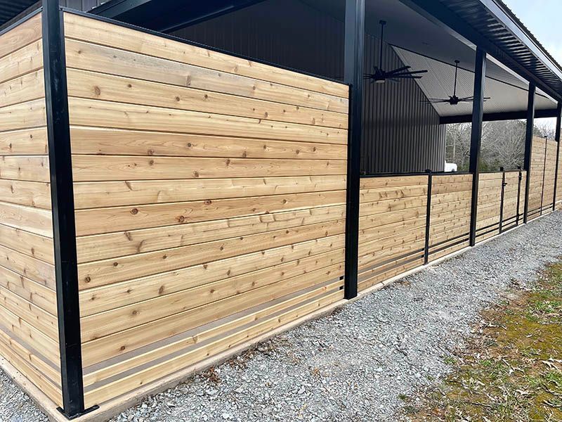A wooden fence surrounds a building with a porch.