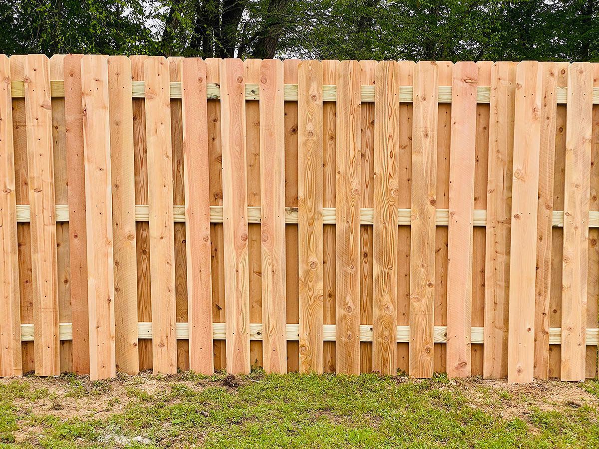 A wooden fence is sitting in the middle of a lush green field.