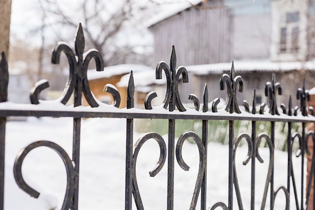 A close up of a wrought iron fence covered in snow.