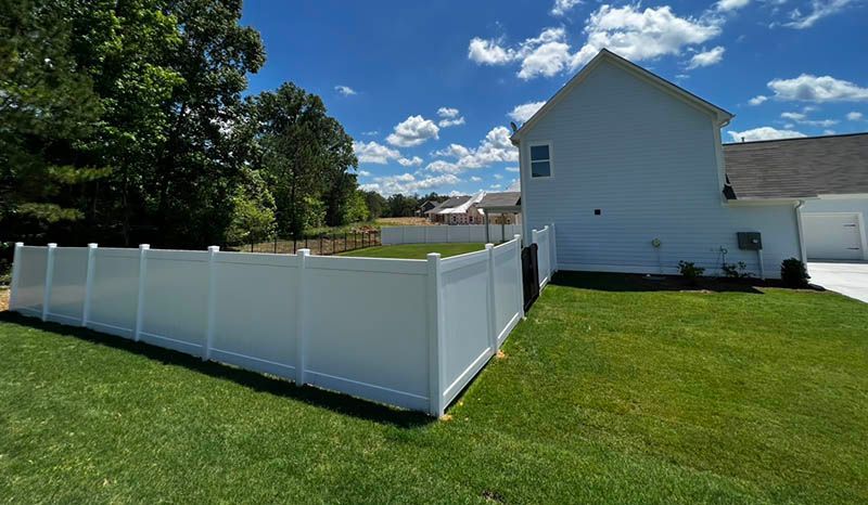 There is a white fence in the backyard of a house.