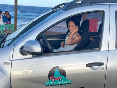 Uma mulher está sentada no banco do motorista de um carro prateado