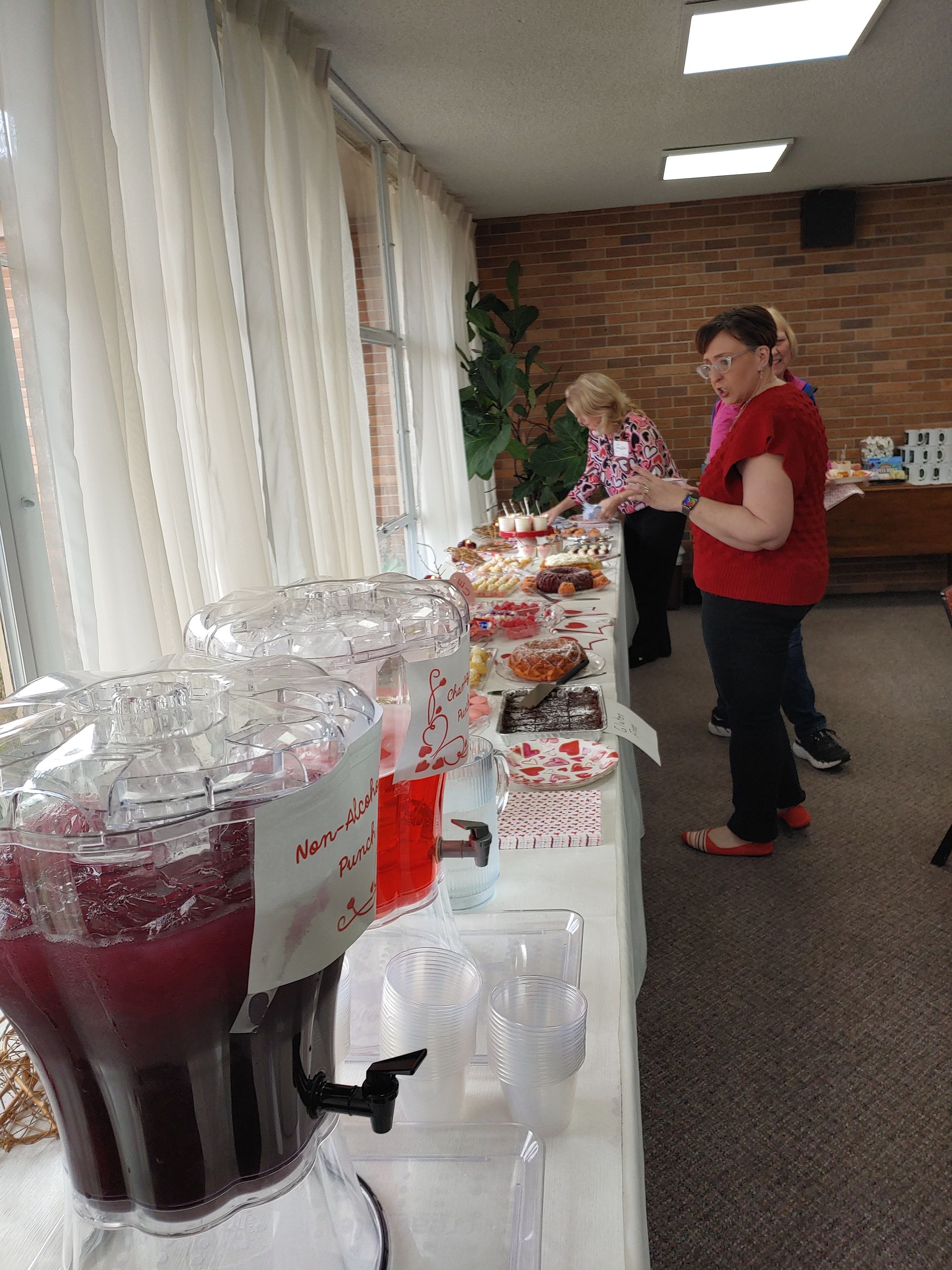 Buffet table with drinks and treats. People serving themselves.