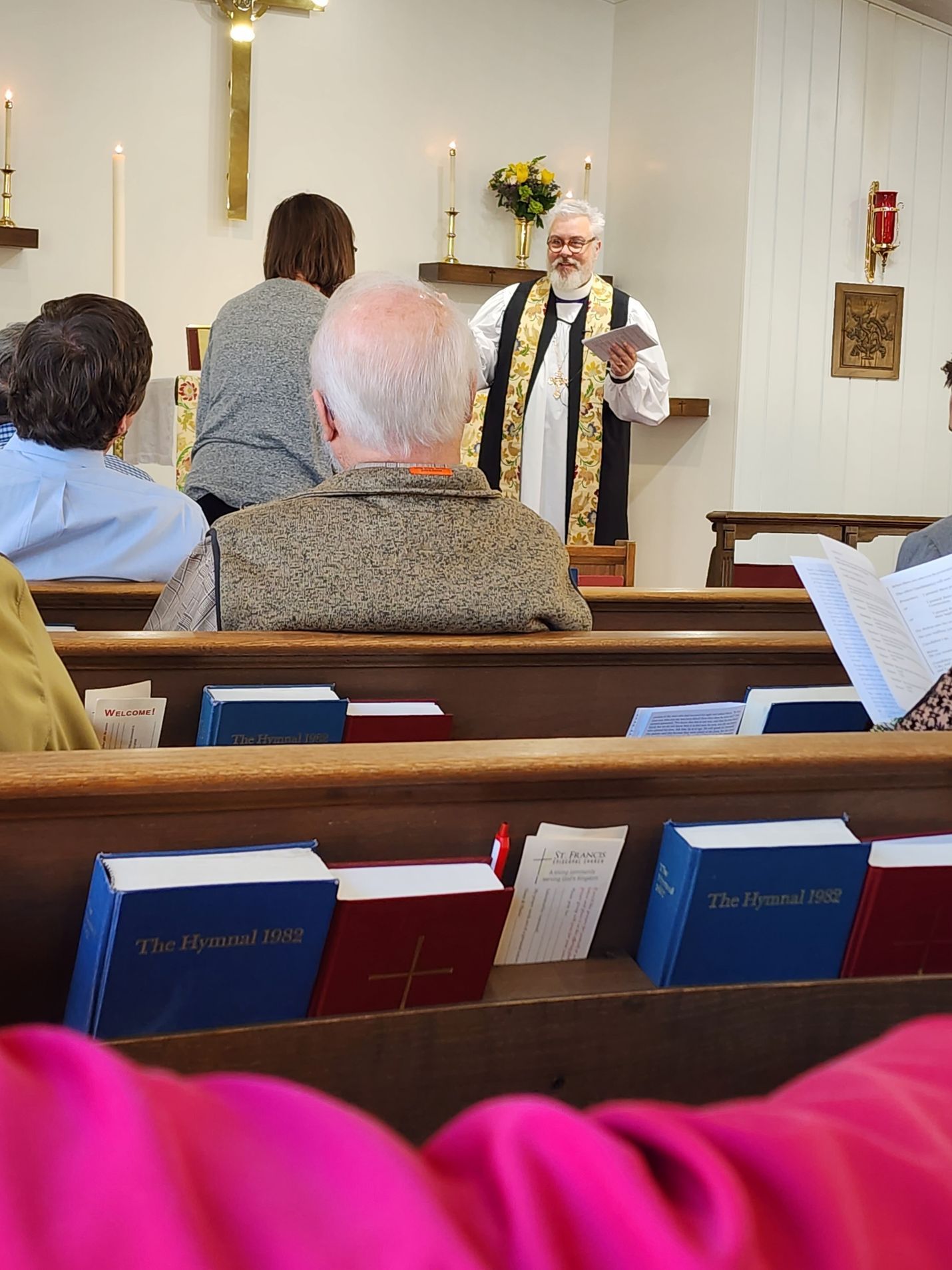 A priest in a church reads to seated congregation.