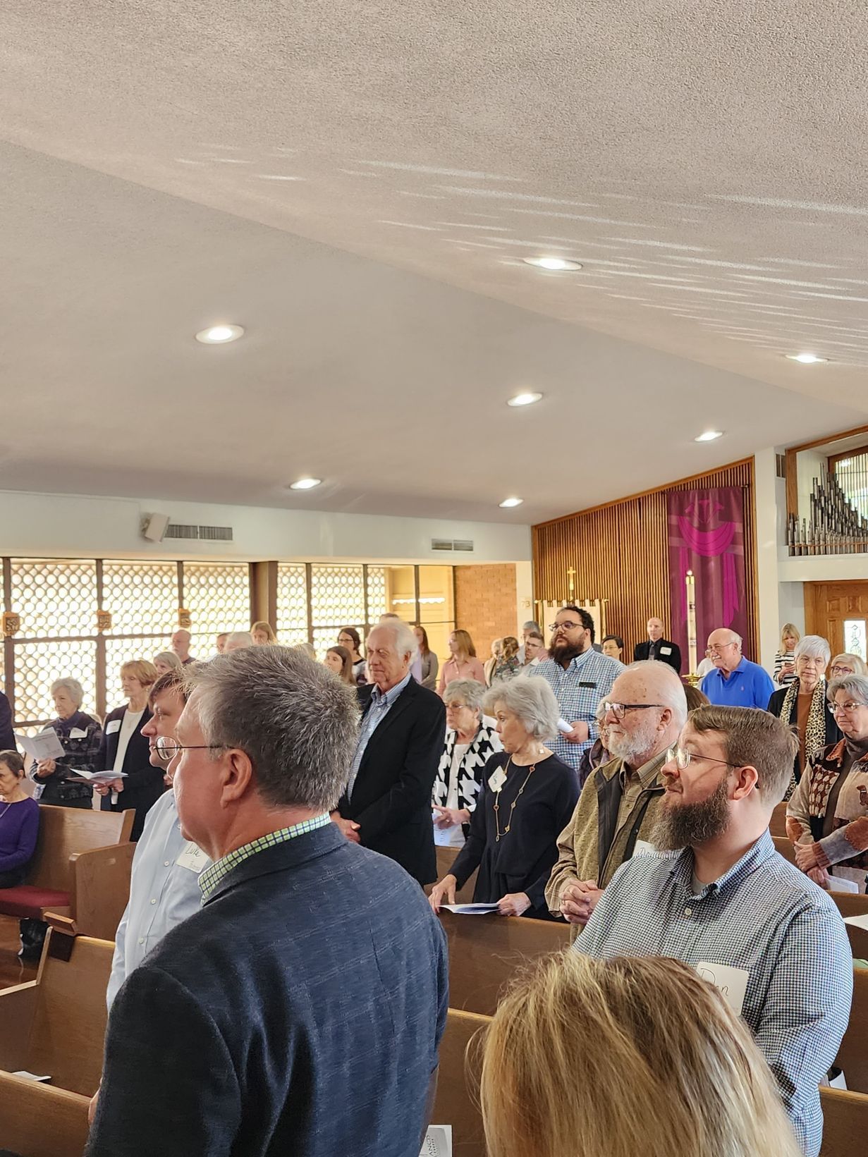 People standing in a church with sunlight shining from above.