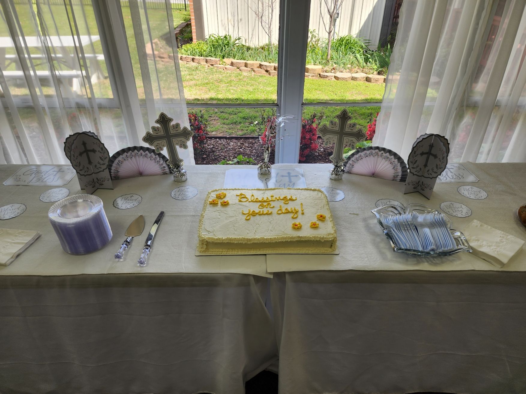 Table set for celebration: Cake, crosses, and other decorations in front of a window.