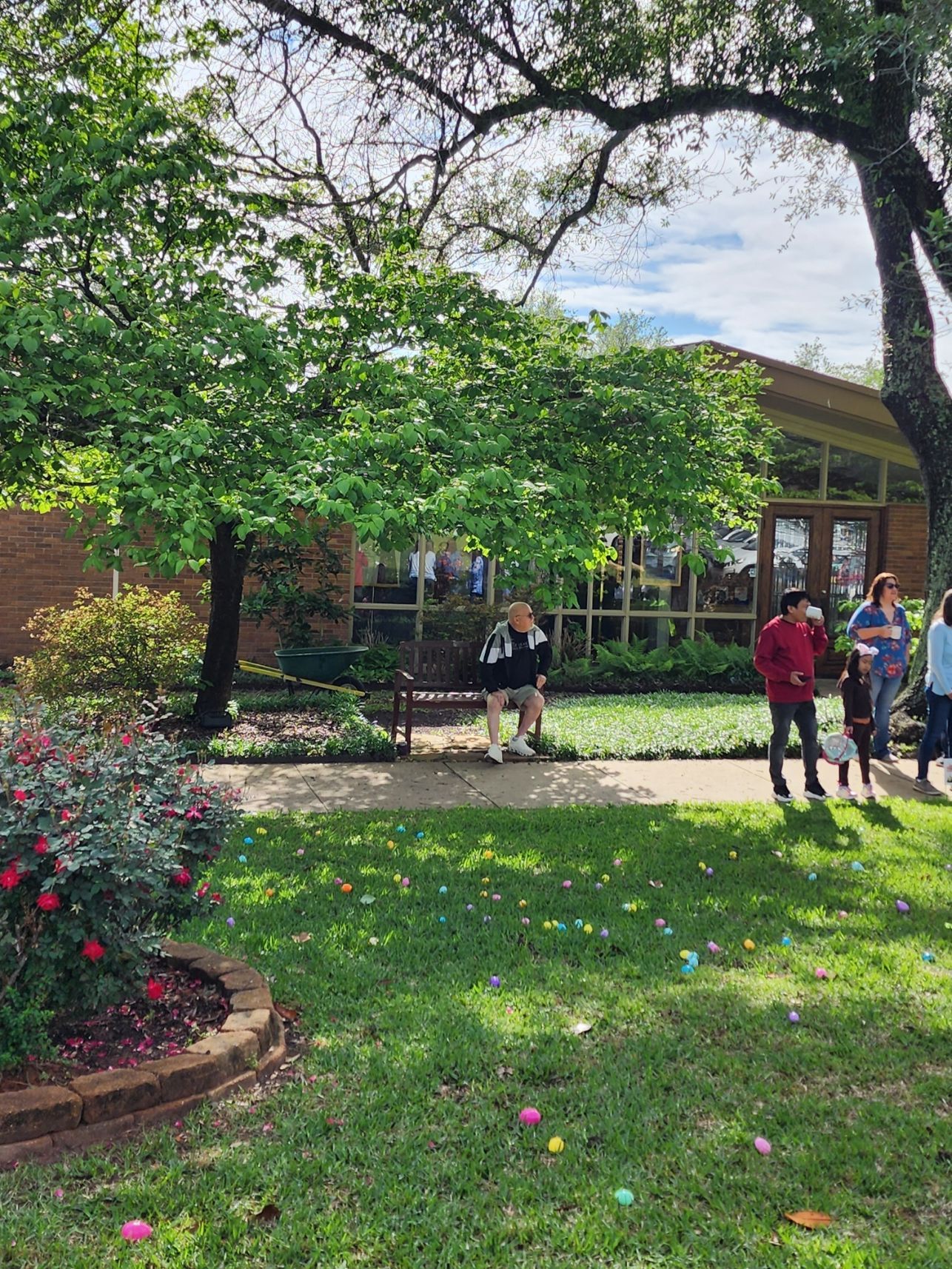 Children hunting for Easter eggs in a grassy yard, brick building in the background.