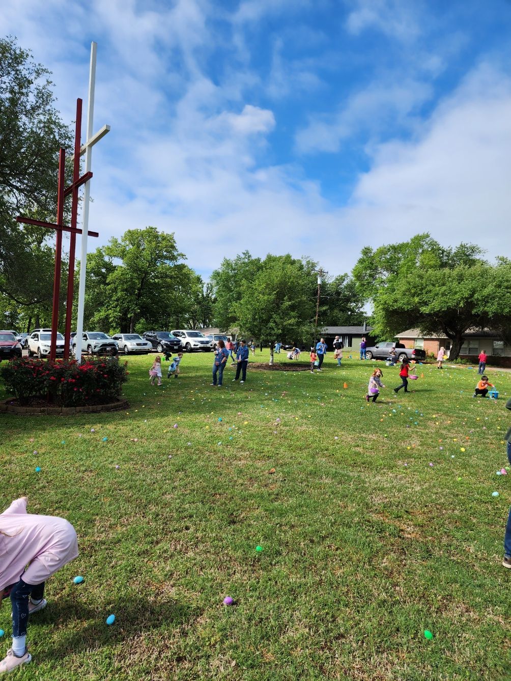Children gather on a lawn, collecting eggs during an outdoor Easter egg hunt.