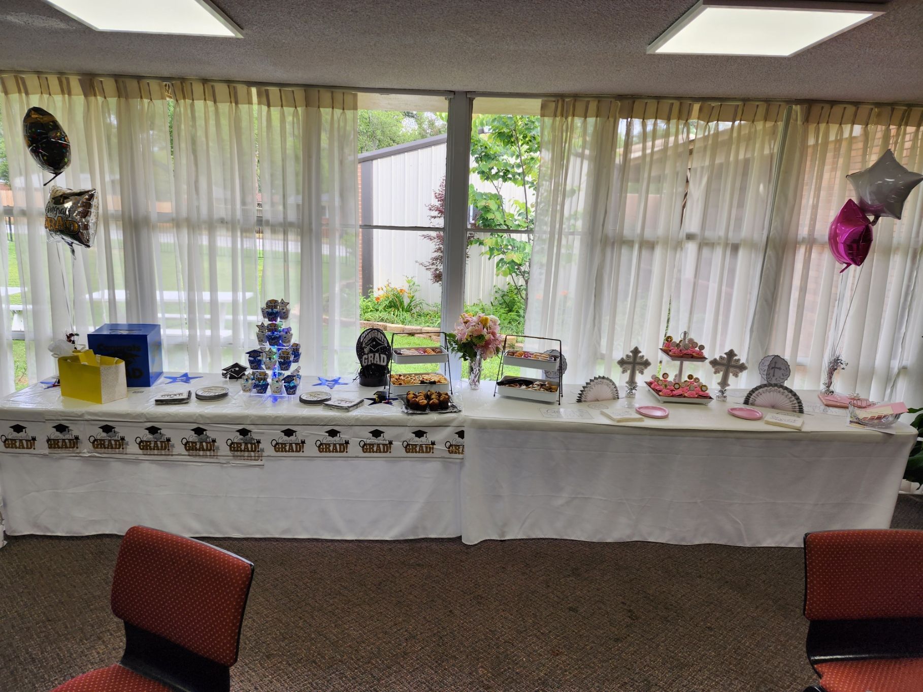 A long table with a white cloth is set for a party, with desserts, gifts, and decorations.