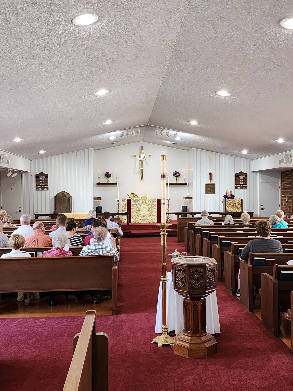 Interior of a church during a service, with people seated in pews facing an altar.