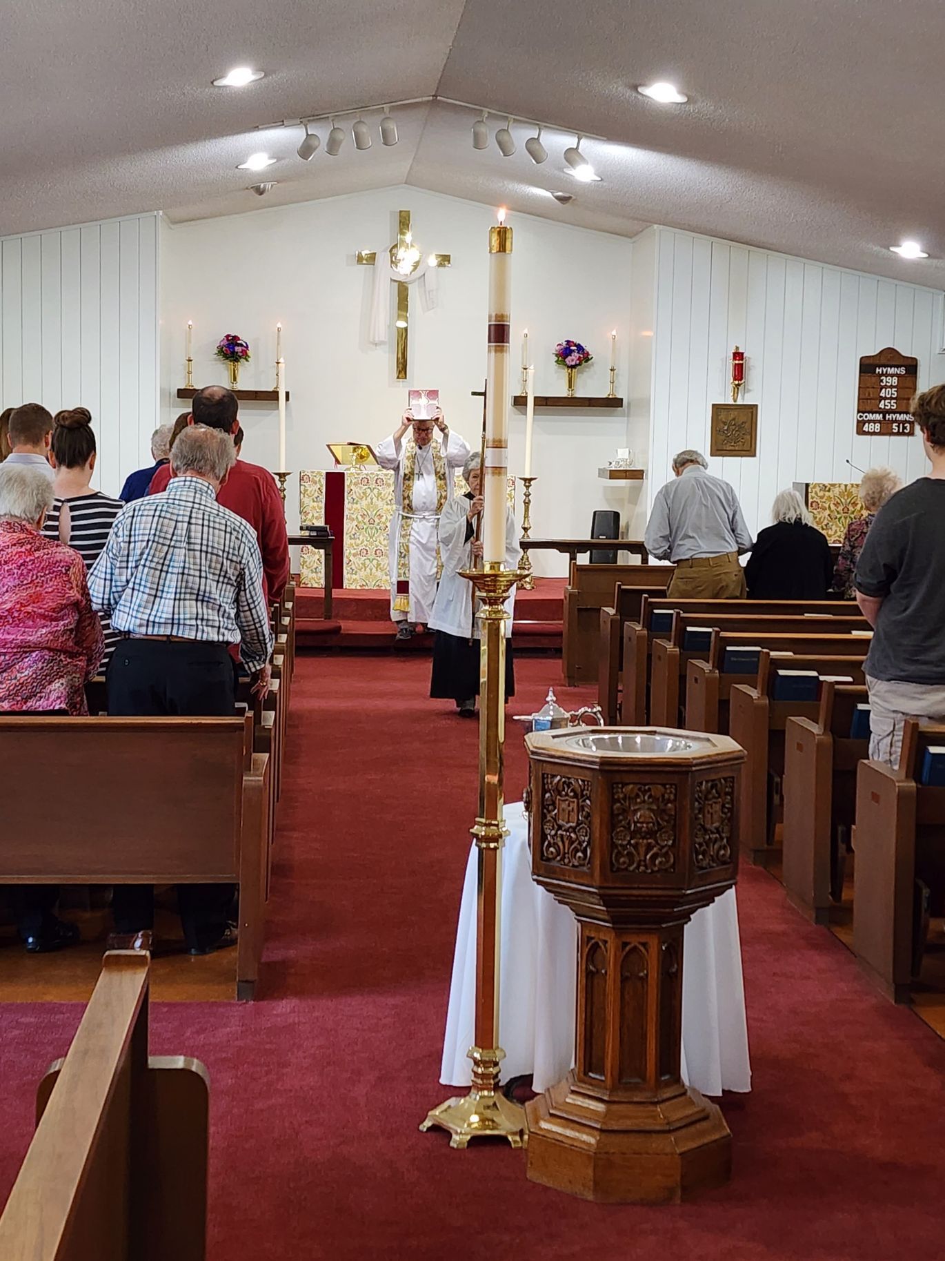 People in a church service with an altar, cross, and candles.