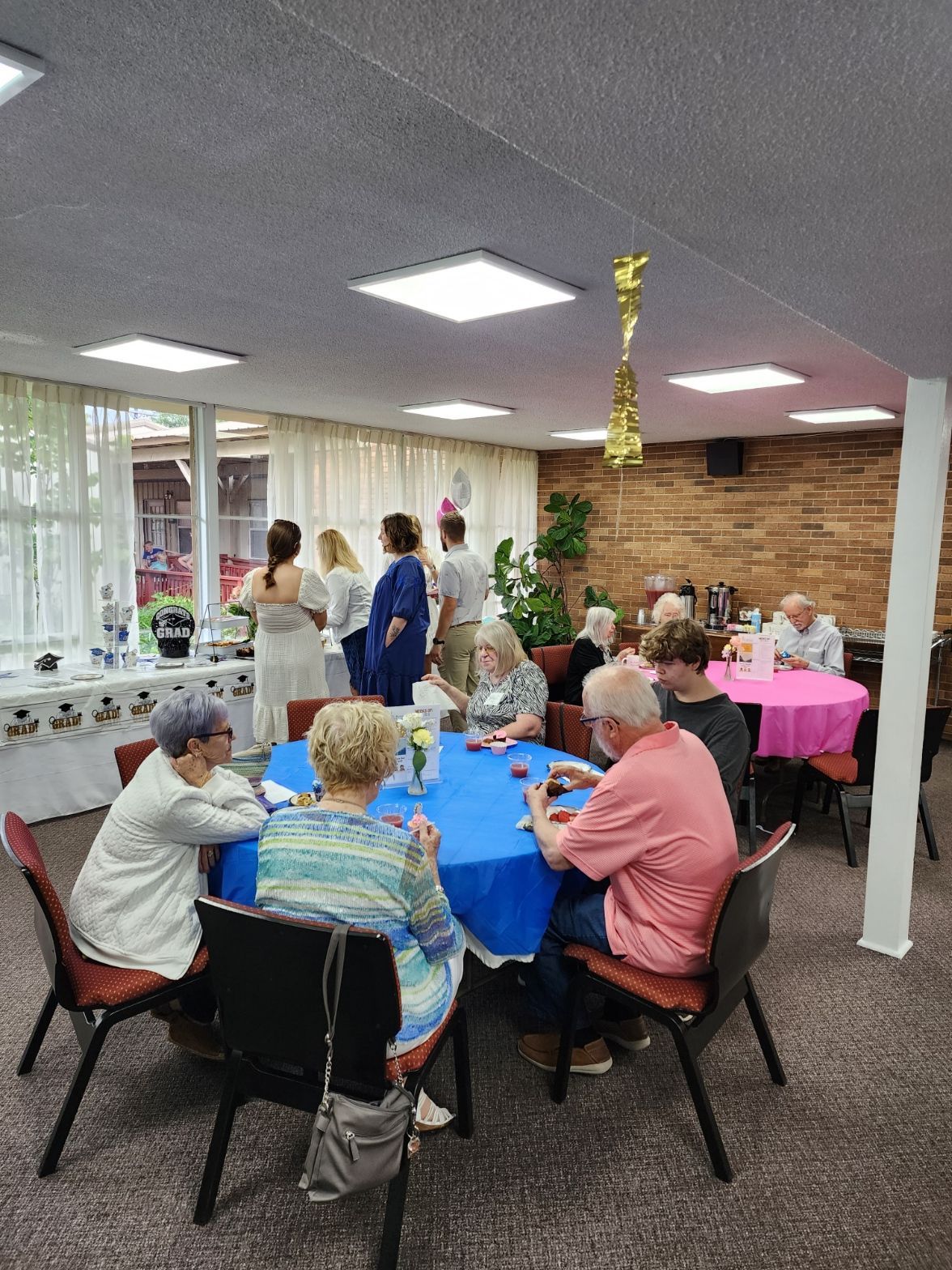 People at tables in a room with a party setting. Some are playing games, others are socializing.