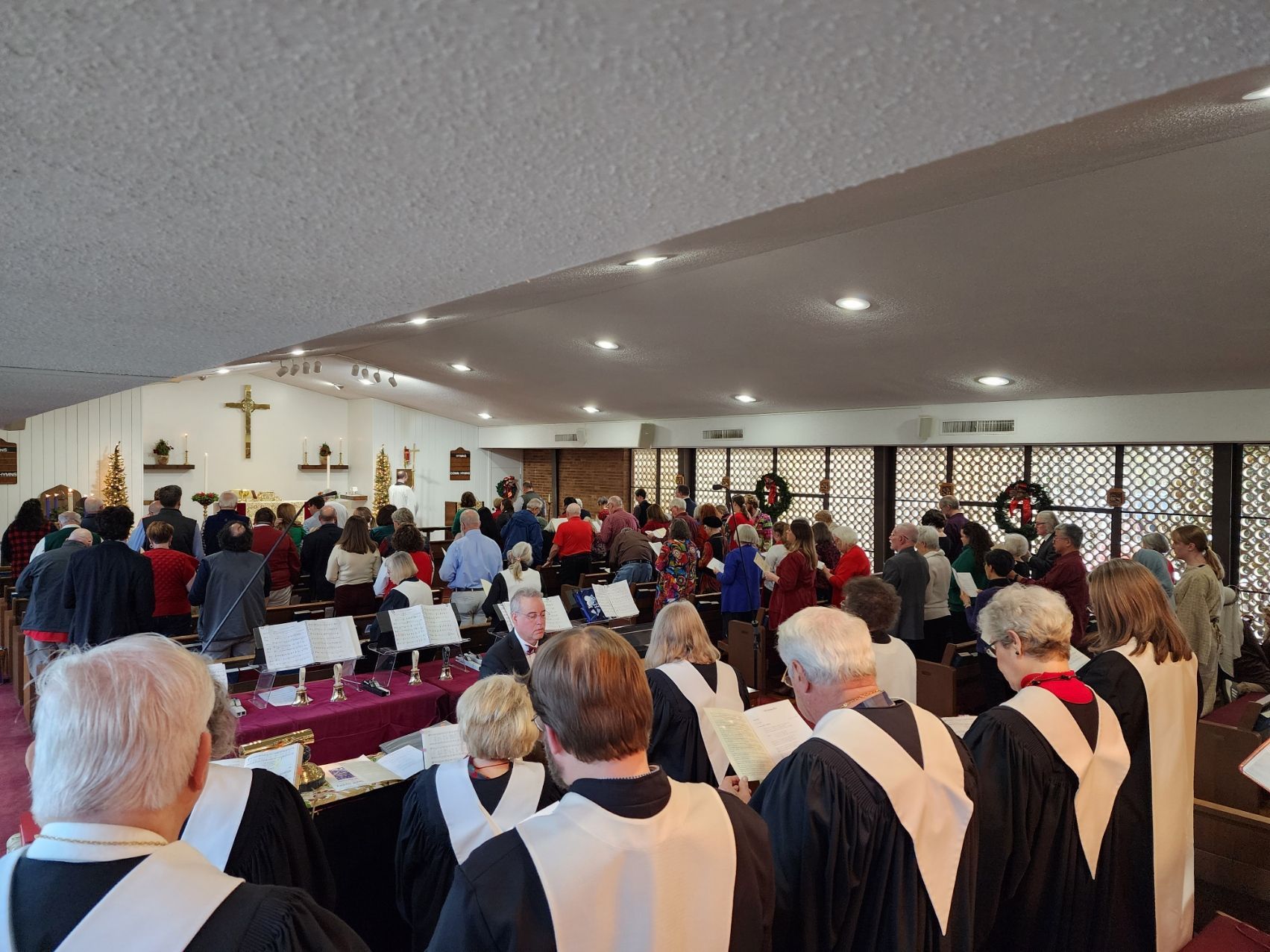 Choir singing in a church, congregation in the background. Many people, Christmas decorations visible.