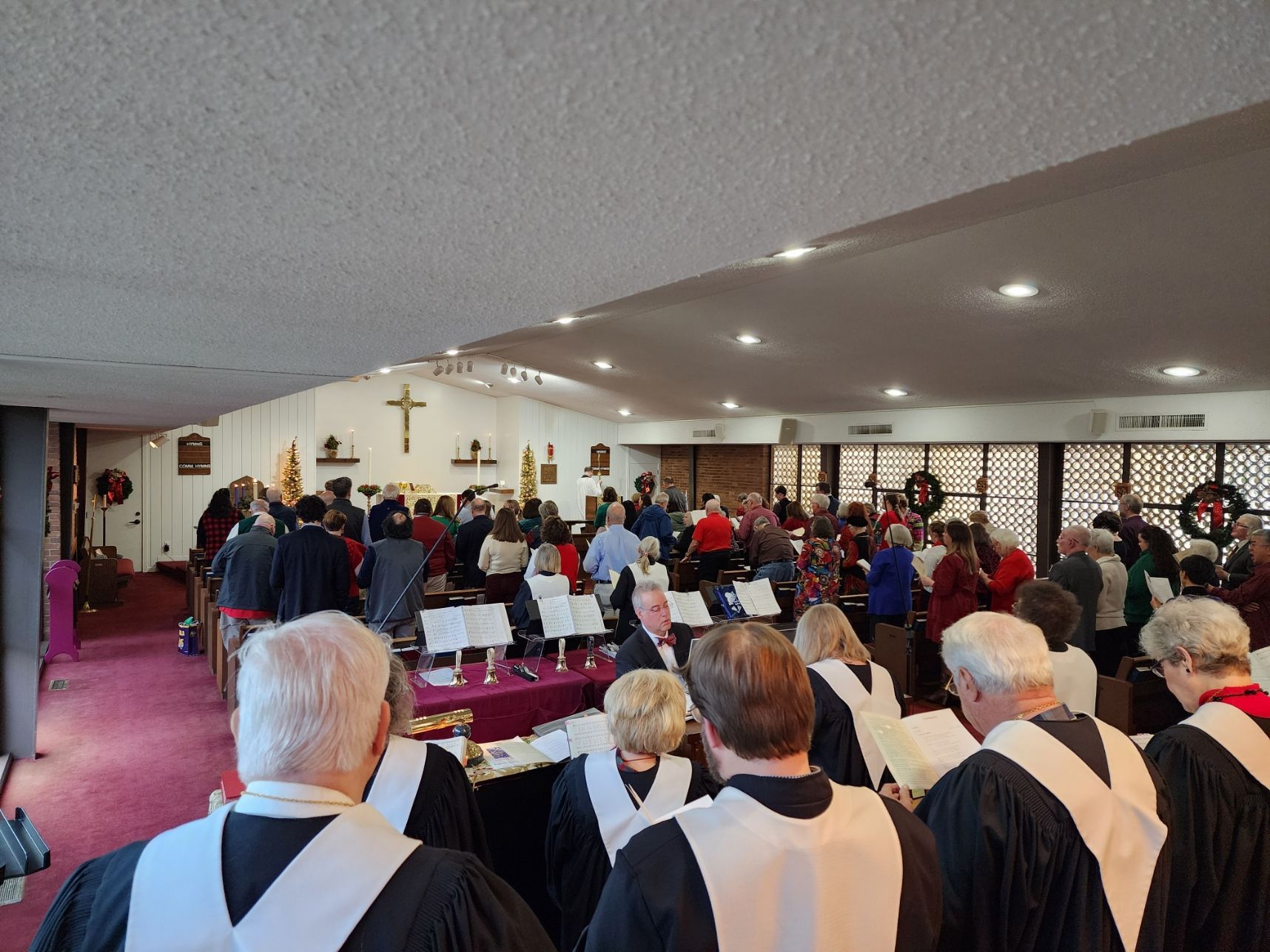Inside a church, a bell choir performs before a congregation.