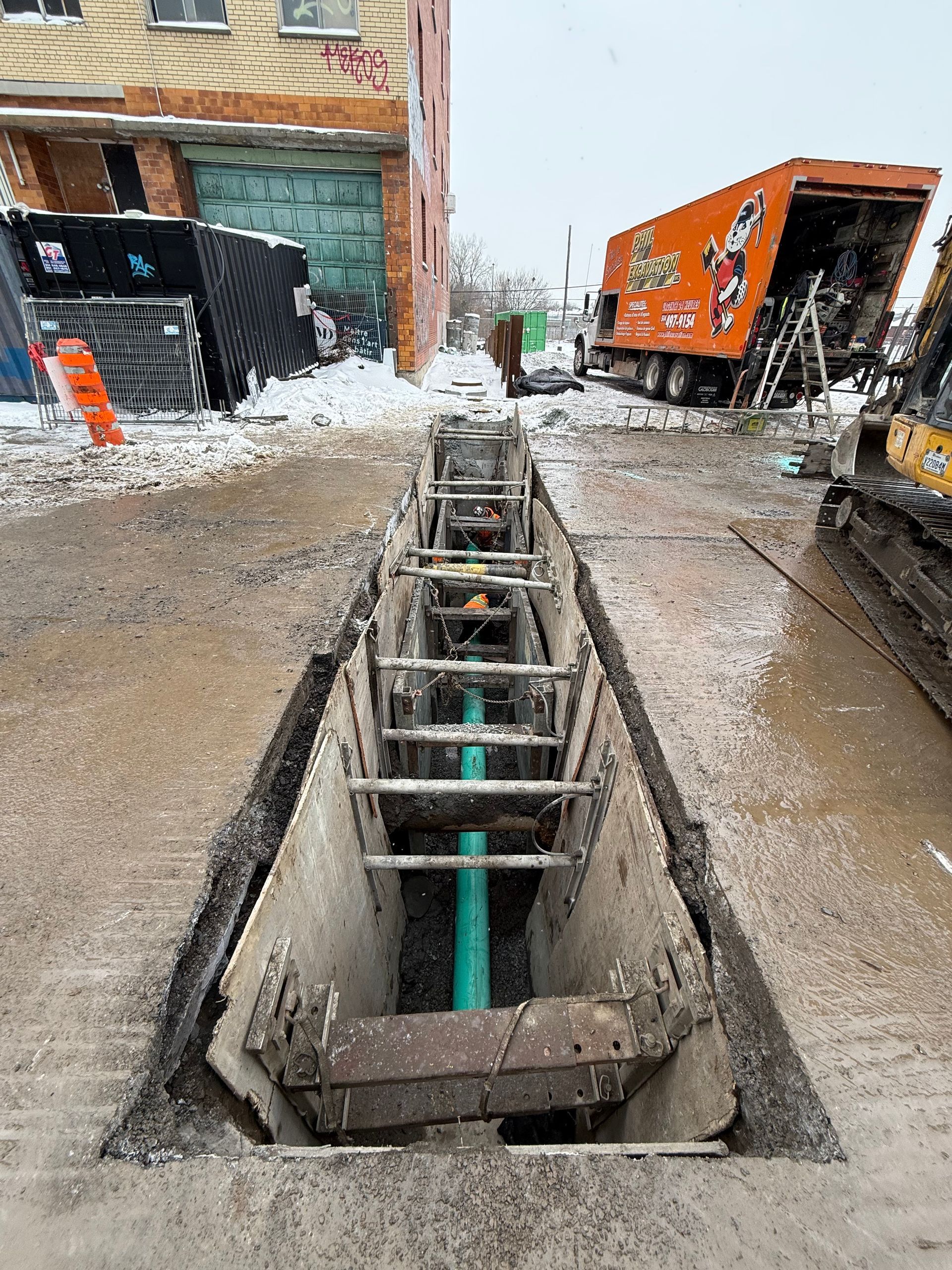 Chantier de construction avec ouvriers, excavatrice et bâtiment en béton partiellement construit par une journée ensoleillée.