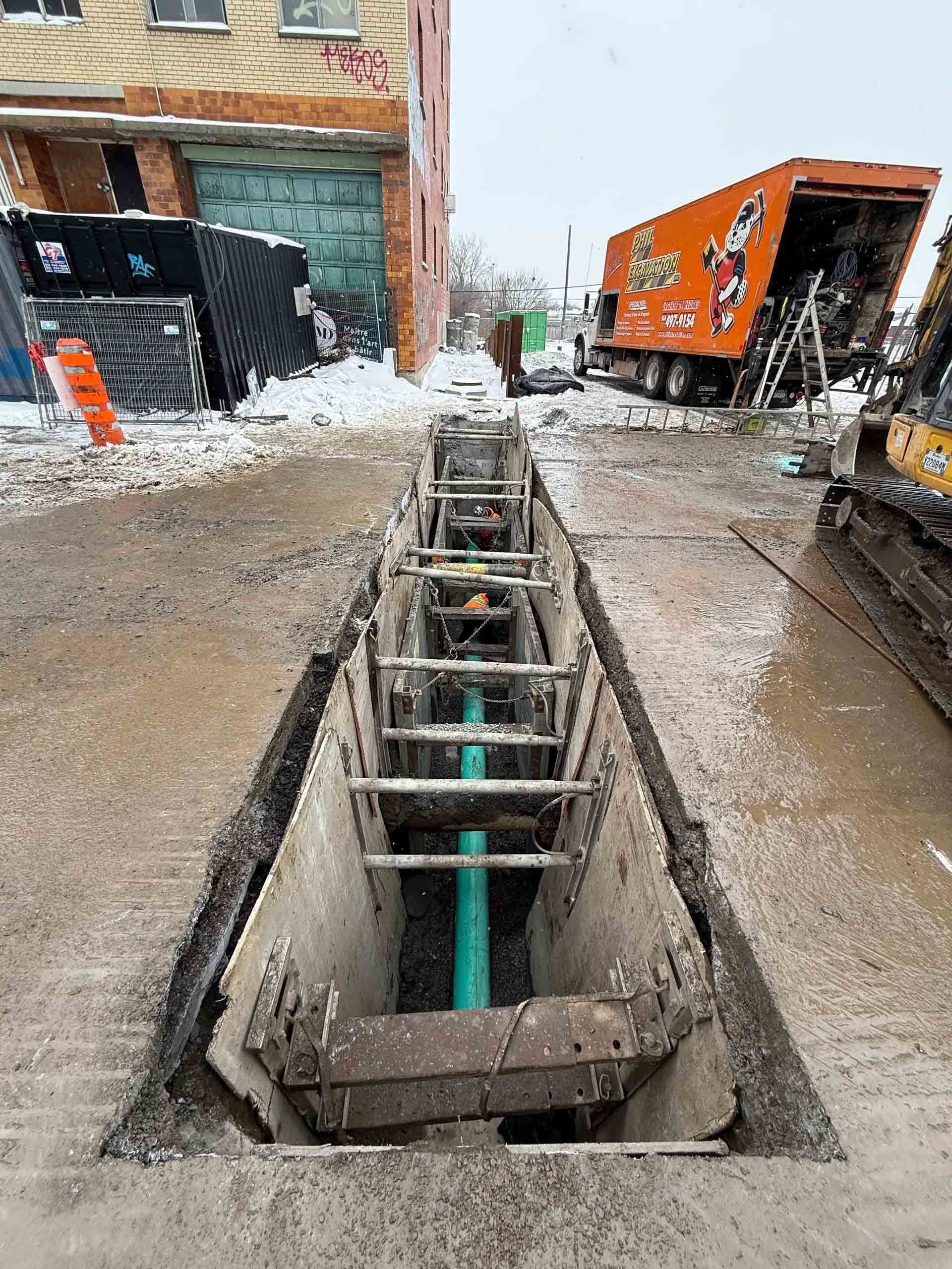 Chantier de construction avec ouvriers, excavatrice et bâtiment en béton partiellement construit par une journée ensoleillée.