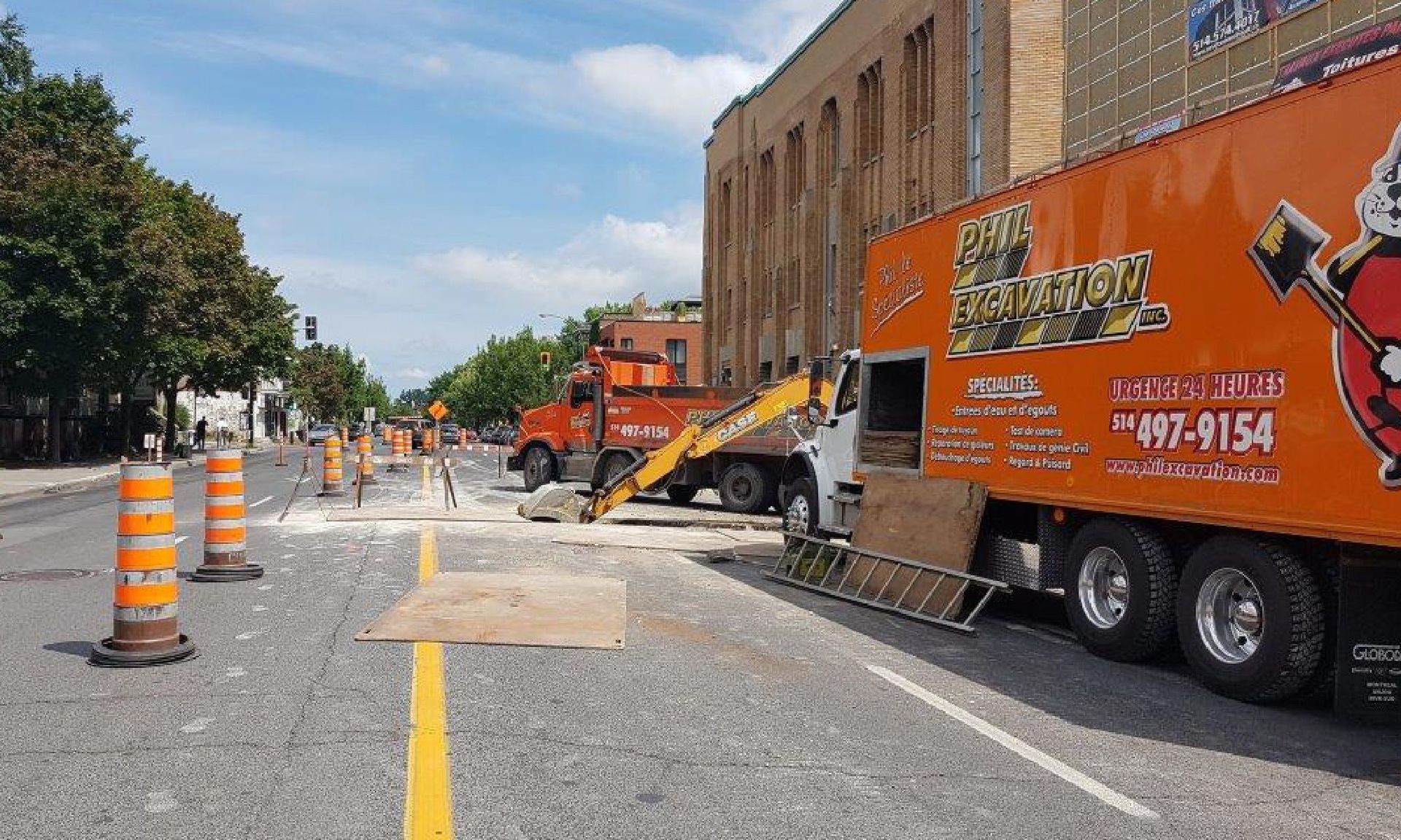 Street construction site: Orange truck, excavator, and cones blocking roadway; debris on the pavement.