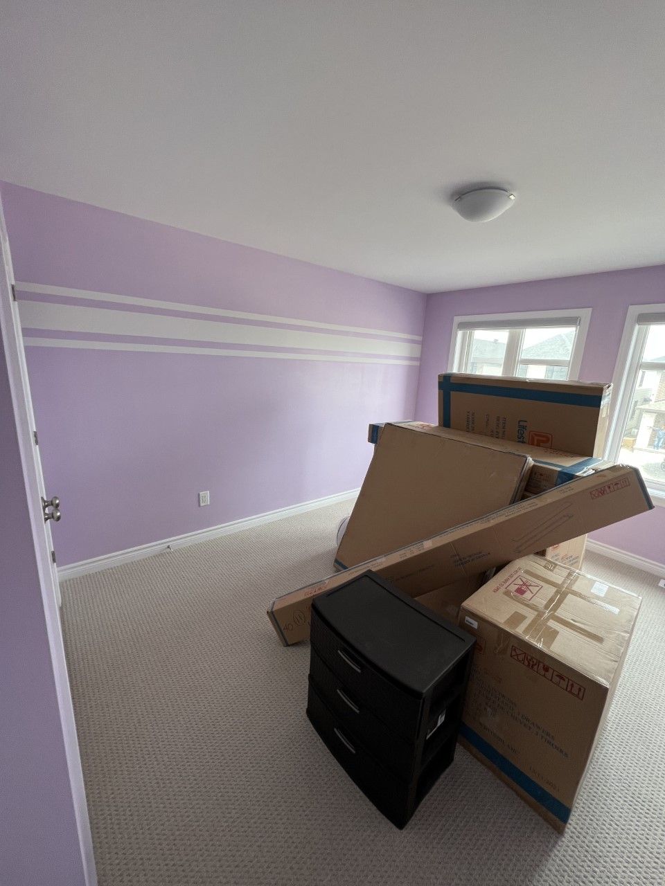 A room with purple walls and boxes on the floor.