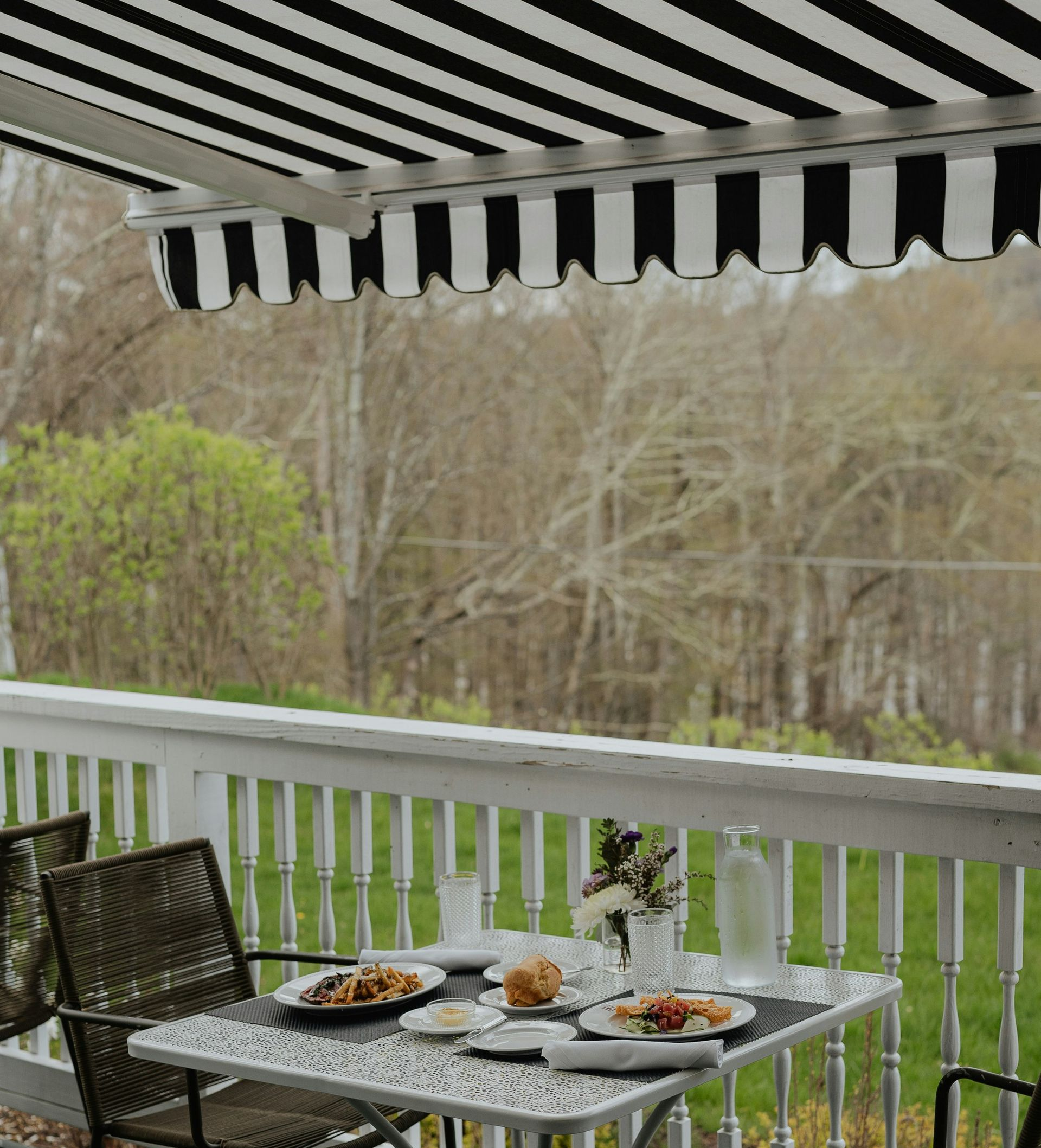 Tan house with black roof, three-car garage, and stone accents, set against a sunset sky.