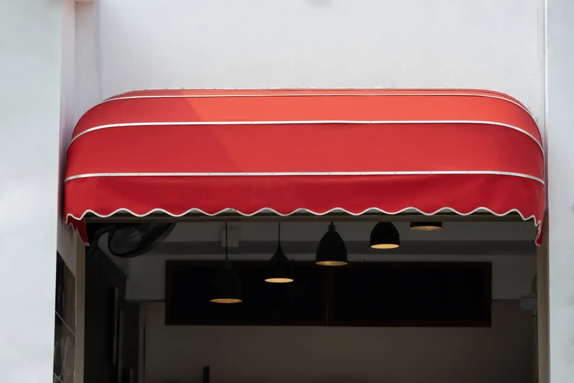 Red and white striped awning over a shop entrance, with hanging lights visible inside.