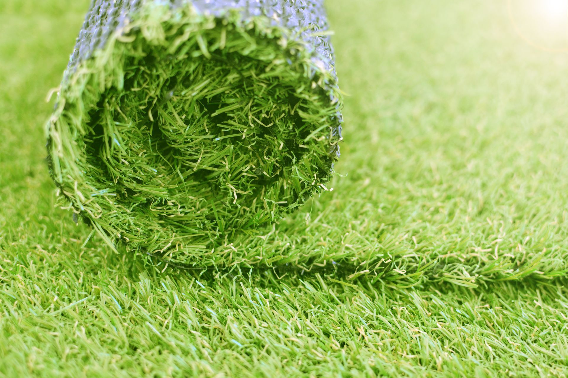 A roll of artificial grass is sitting on top of a lush green field.