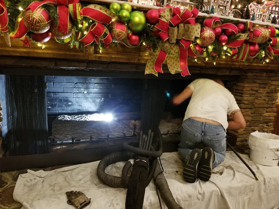 Person cleaning fireplace. Fireplace has holiday decorations above.