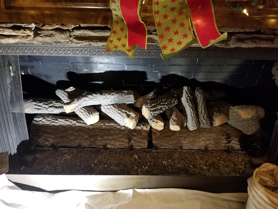 Fireplace with decorative logs and red/green holiday ribbon.
