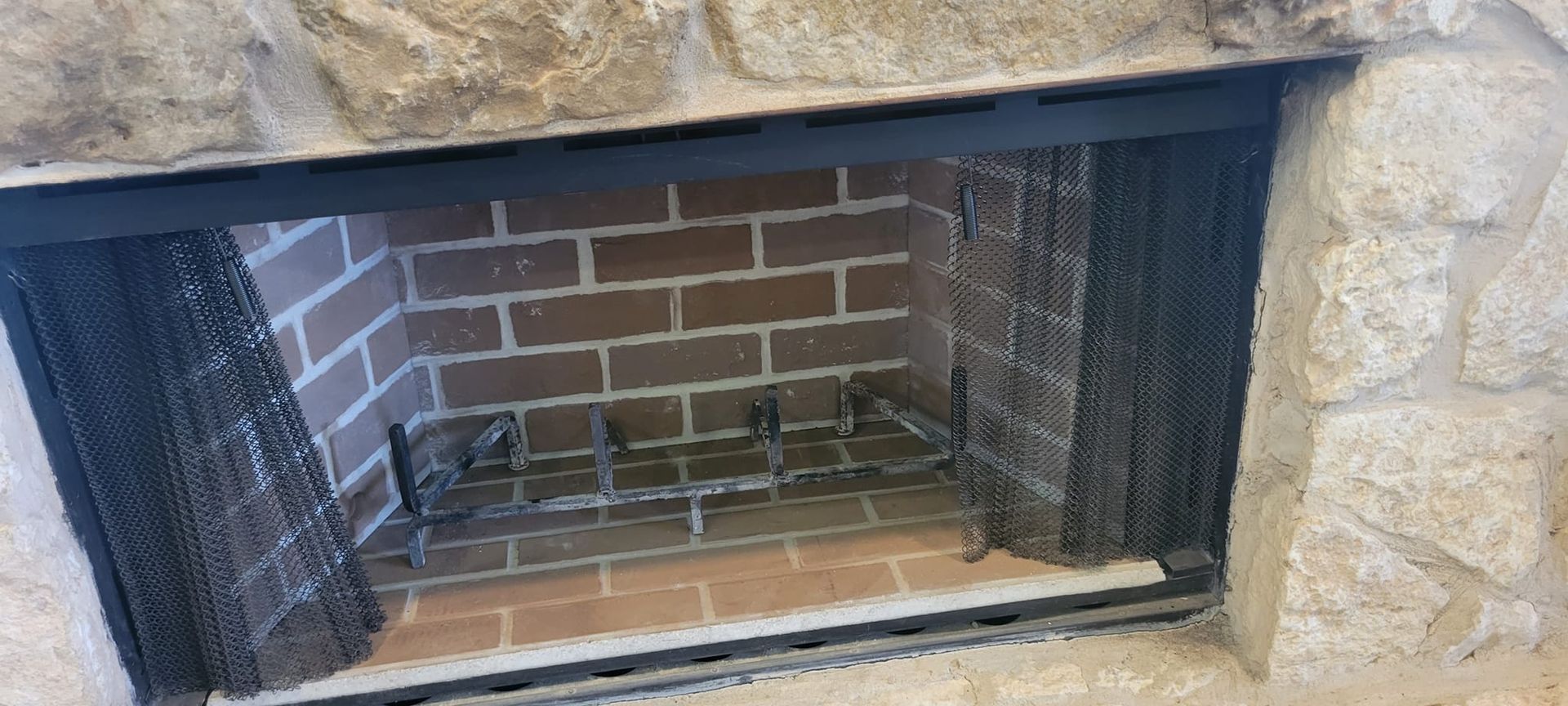 A brick fireplace with a metal grate and a stone surround.