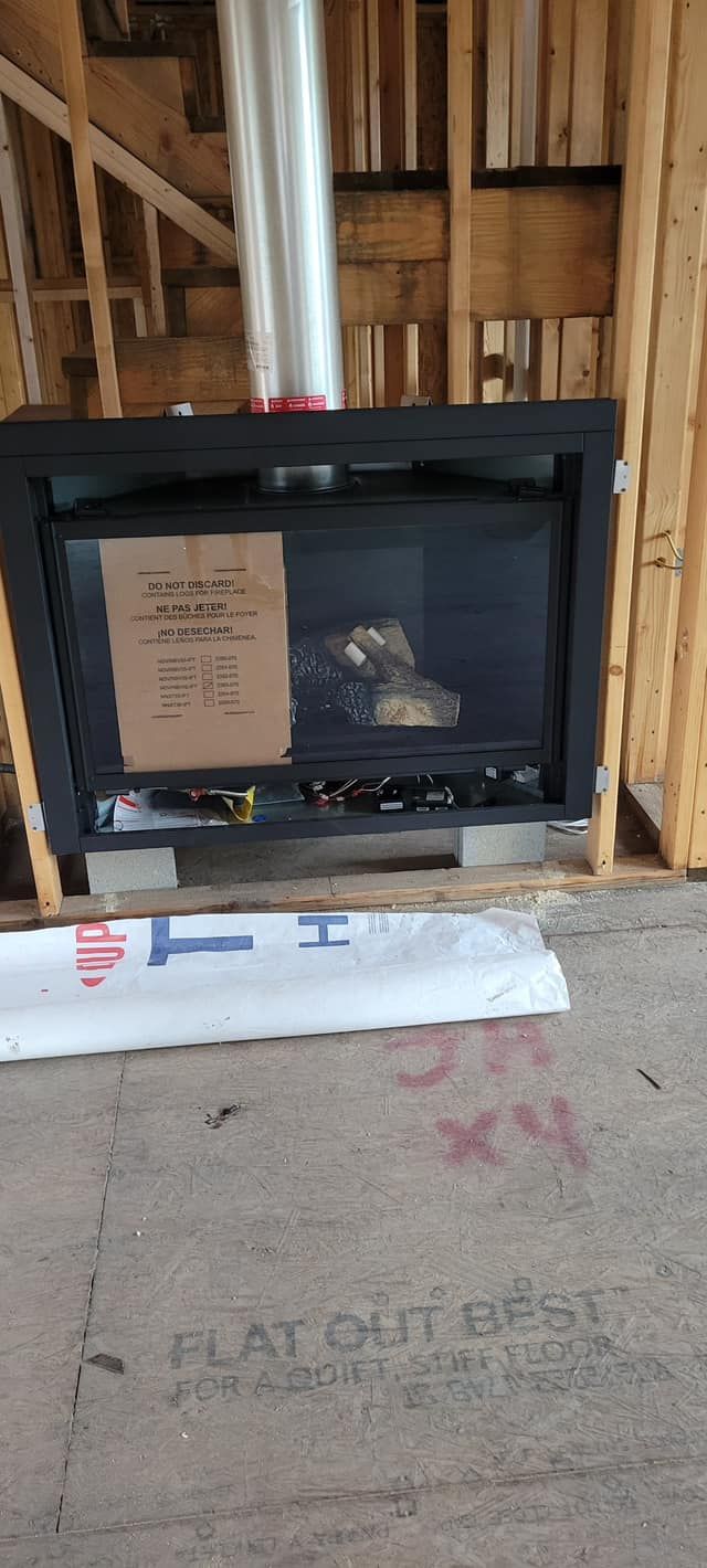 A fireplace unit installed in a new construction house. It is black and has a chimney. 