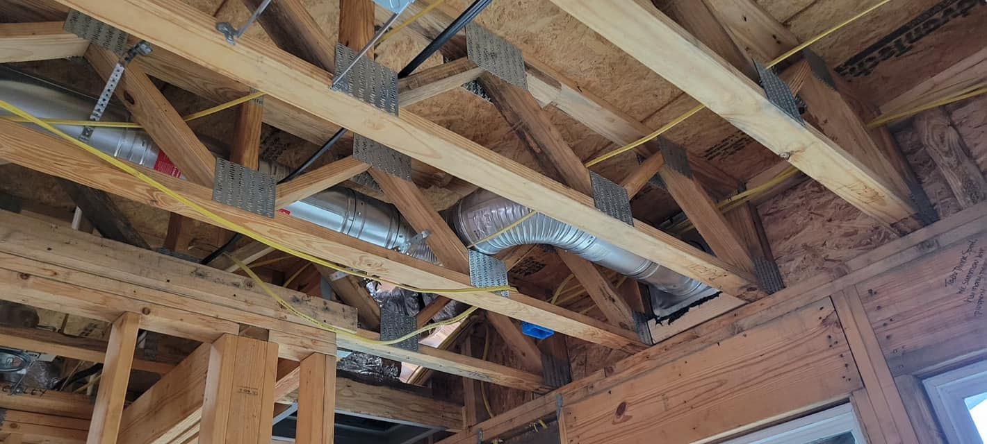 Wooden roof trusses and ductwork installed during construction.