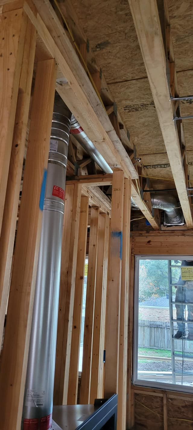 Interior view of a building under construction. A metal flue pipe runs vertically. 